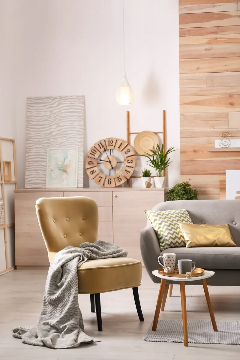 Staged living room with a gold velvet accent chair, grey sofa, wood feature wall and styled sideboard