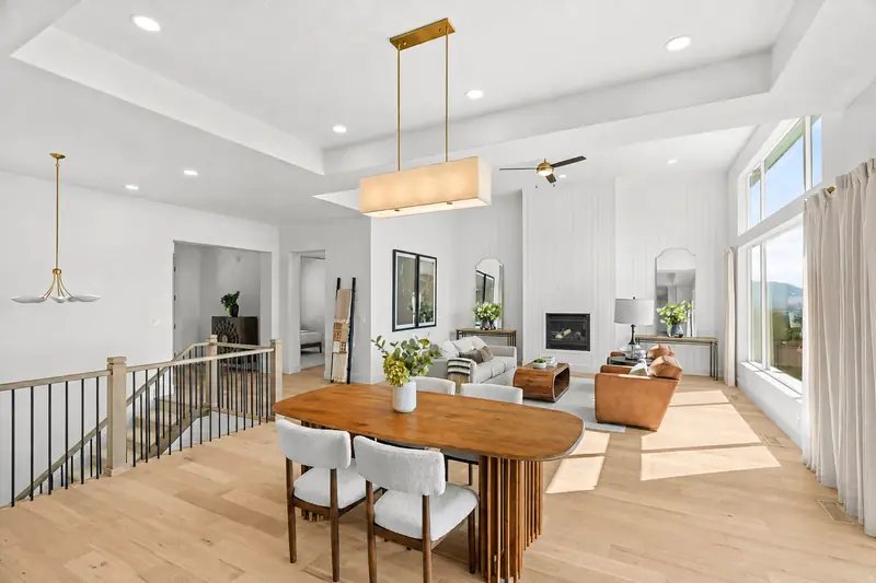 Staged great room with a wood dining table, boucle chairs, layered living room seating and a white shiplap fireplace